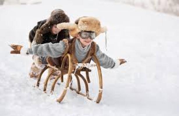 Bambini giocano con una slitta sulla neve.