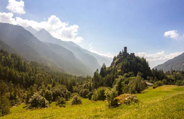 Castle on a hill surrounded by mountains and forests.